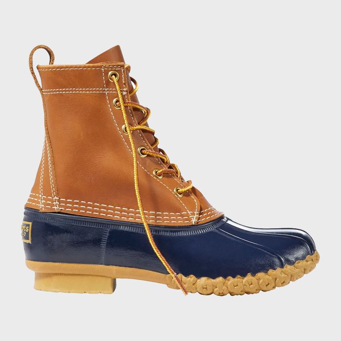 A brown and navy boot features laces and detailed stitching in a studio setting with a light gray background.