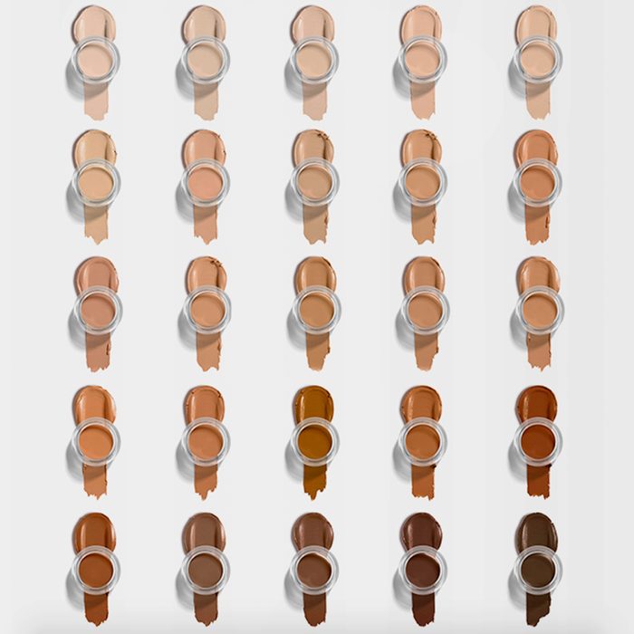 Various foundation shades, arranged neatly in rows, with jars placed above corresponding swatches on a white background.