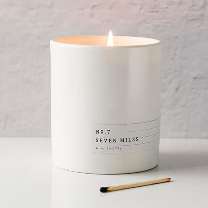 A lit white candle labeled 