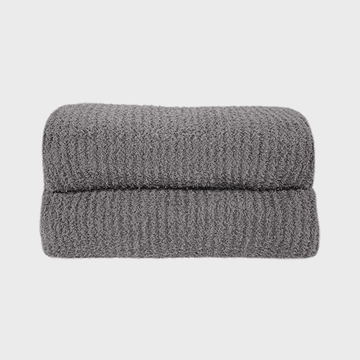 A folded, gray towel sits against a plain white background, displaying a textured, ribbed pattern.