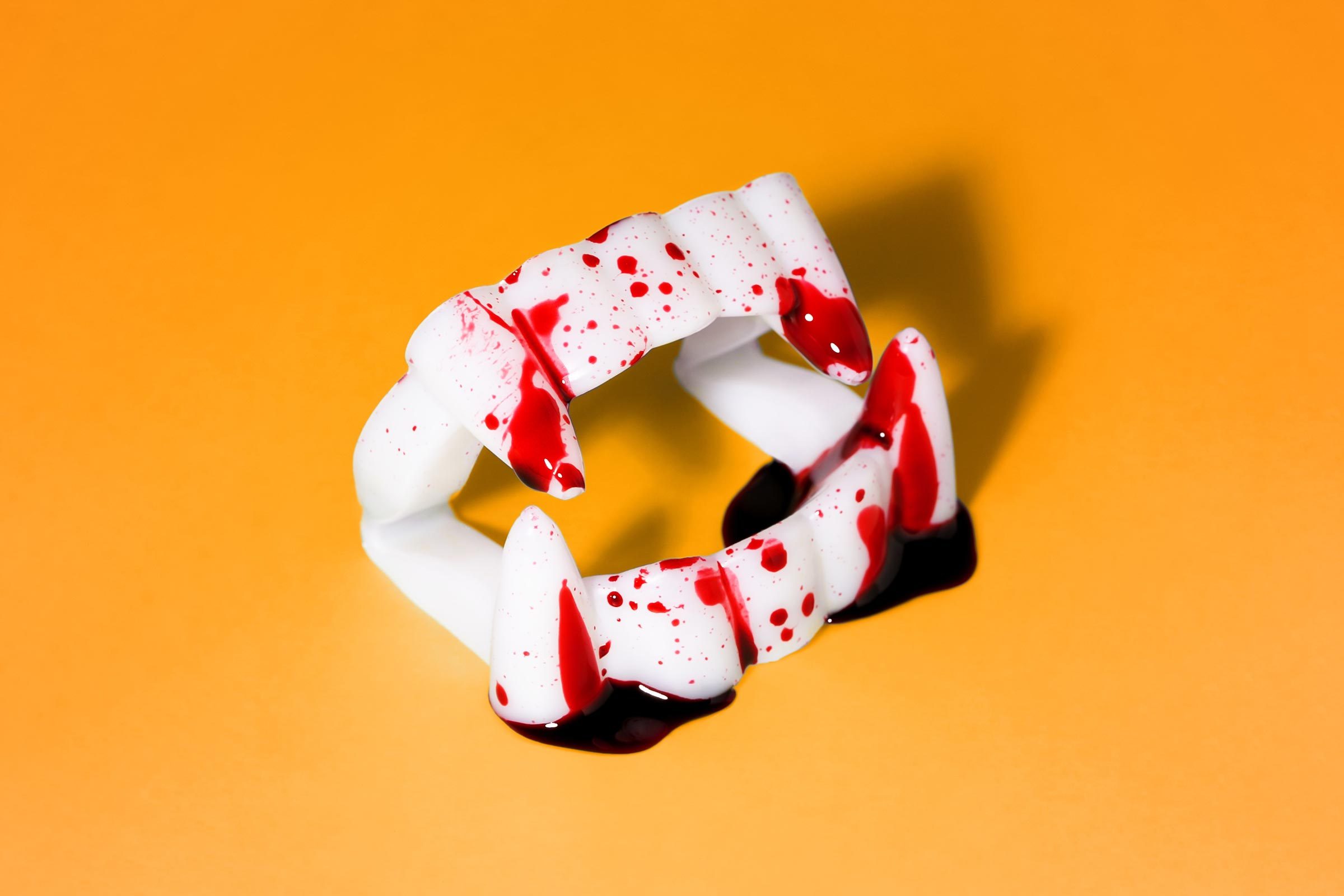 Fake Blood On Vampire Teeth On Orange Background 