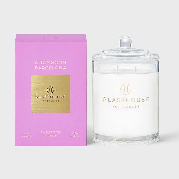 Glass candle with lid sits beside a pink box labeled 