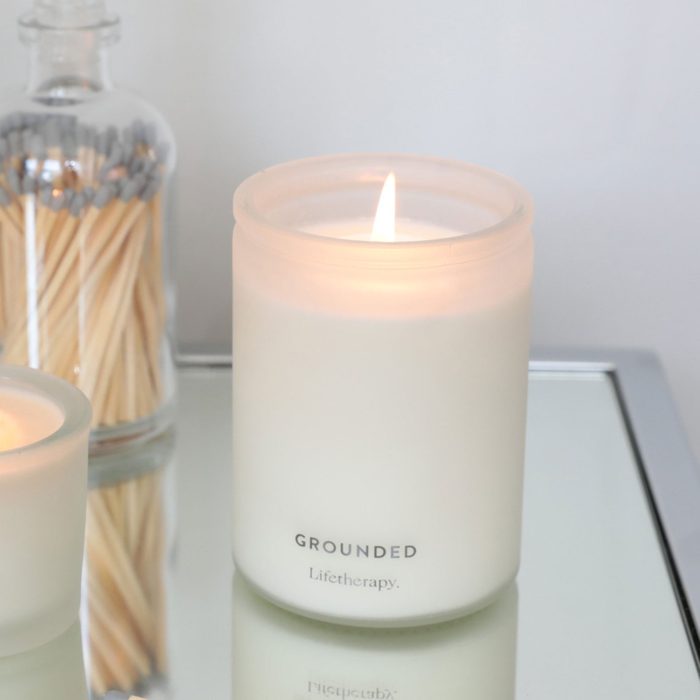 A lit white candle labeled 