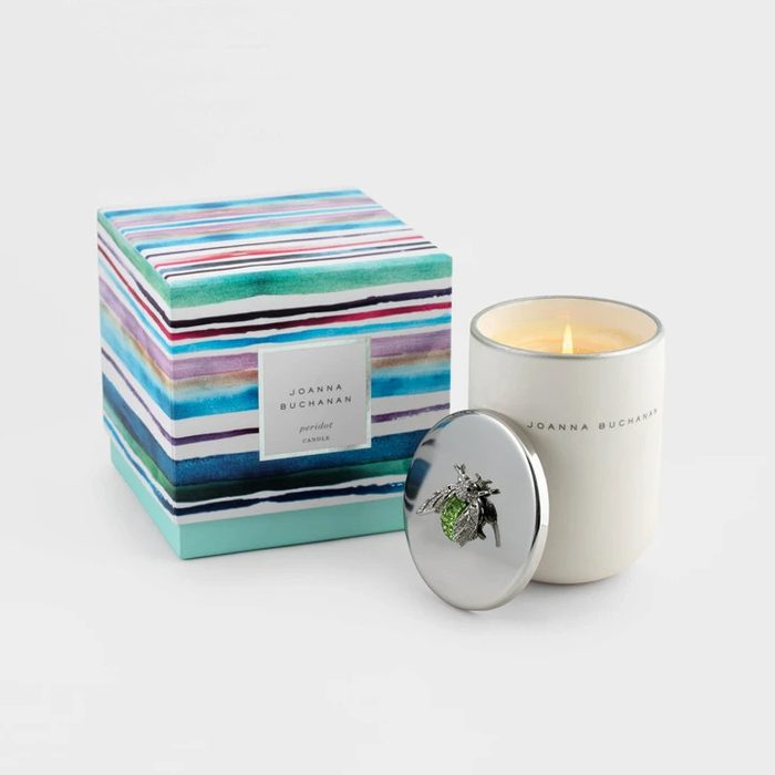 A lit candle sits beside a striped box, featuring the label 