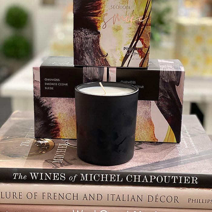 A black candle sits on stacked books surrounded by decorative boxes with text: 