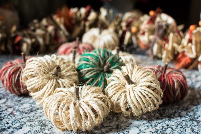 Twine-wrapped bundles resemble pumpkins resting on a speckled countertop, with blurred autumnal decorations in the background.