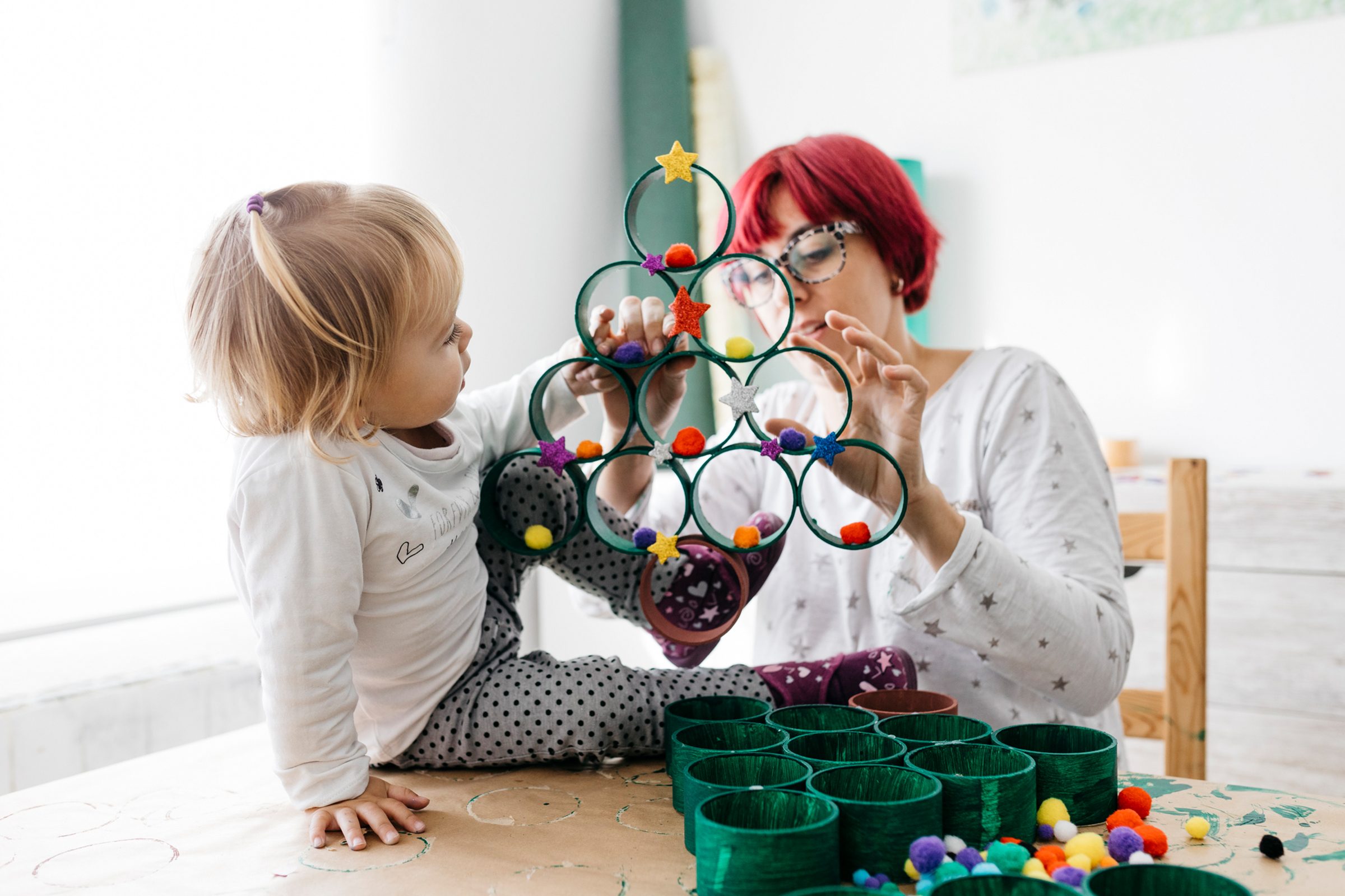 Mother and daughter doing crafts at home with accessories to make a Christmas tree