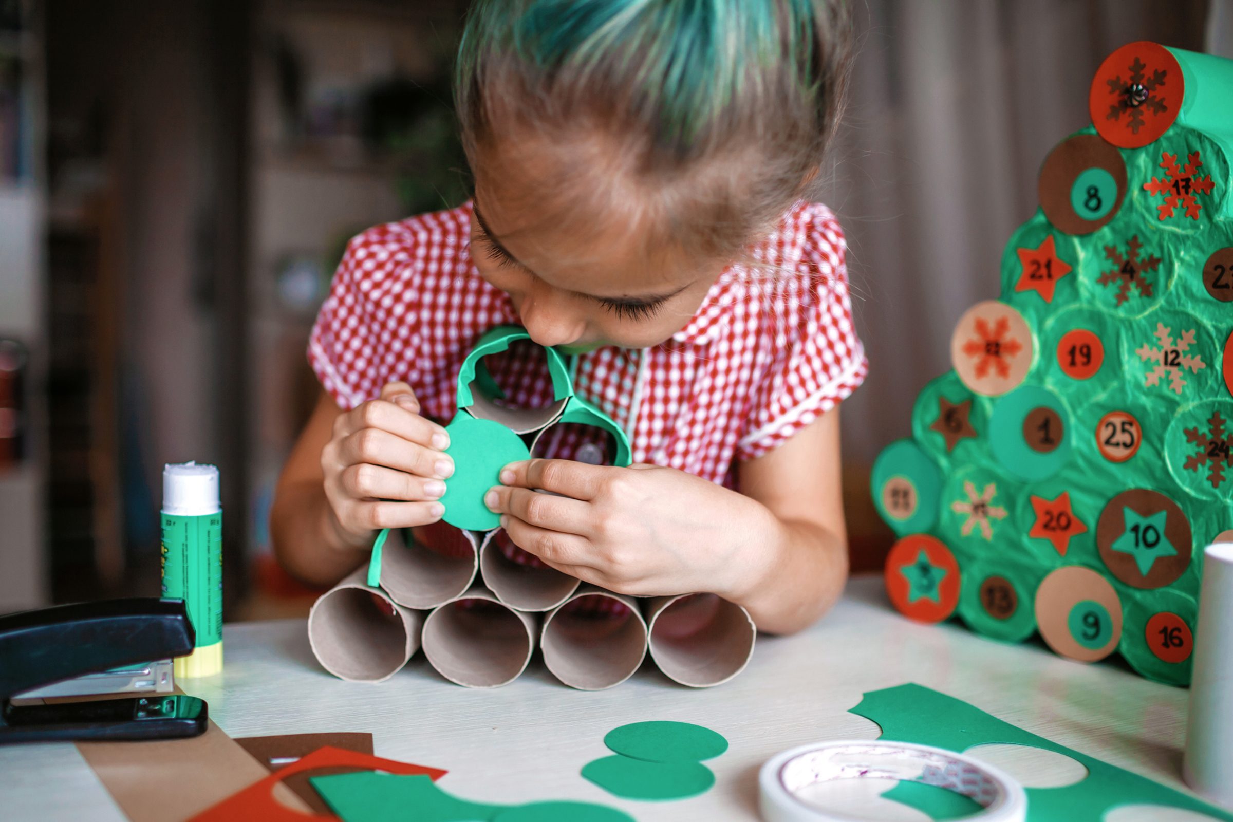 Little girl making Christmas Tree Calendar out of toilet paper rolls