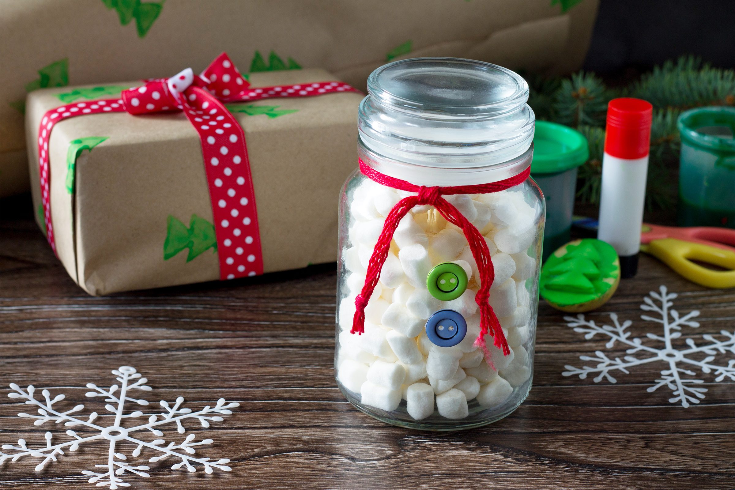 The child is making Christmas presents. Christmas gift box and snowman sweets
