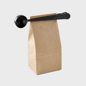 Metal scoop clips a folded paper bag, labeled 