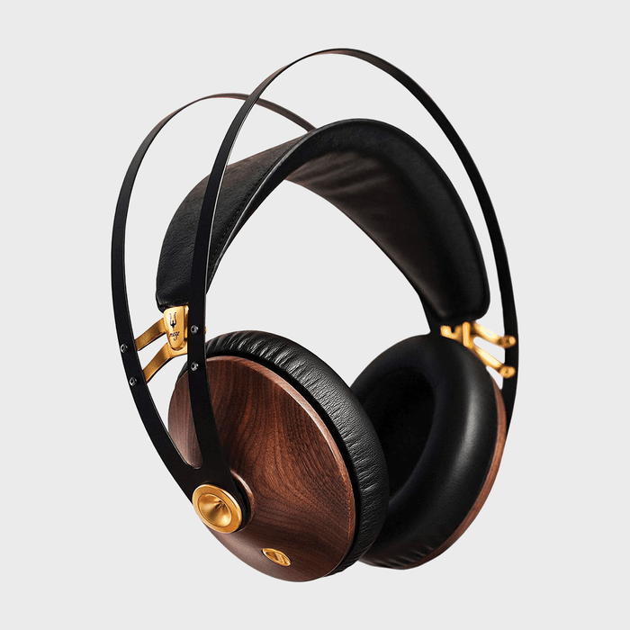 Headphones suspended with black and gold metal frame, featuring wooden earcups, displayed against a plain, light gray background.
