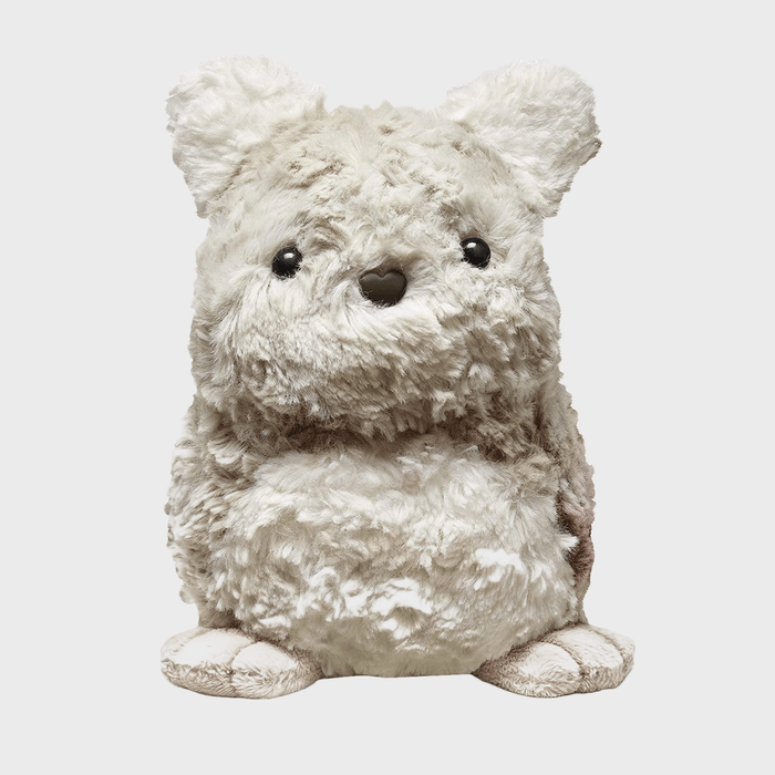 A fluffy, beige teddy bear sits upright against a plain white background, featuring black eyes and a heart-shaped nose.