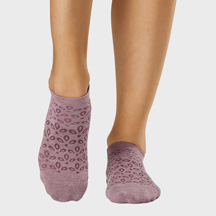 Feet wearing purple patterned ankle socks, standing on a light background.