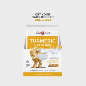 Turmeric latte mix packets displayed in a box featuring turmeric, ginger illustration, and steam graphic, with text emphasizing daily deliciousness, caffeine-free, non-GMO qualities.