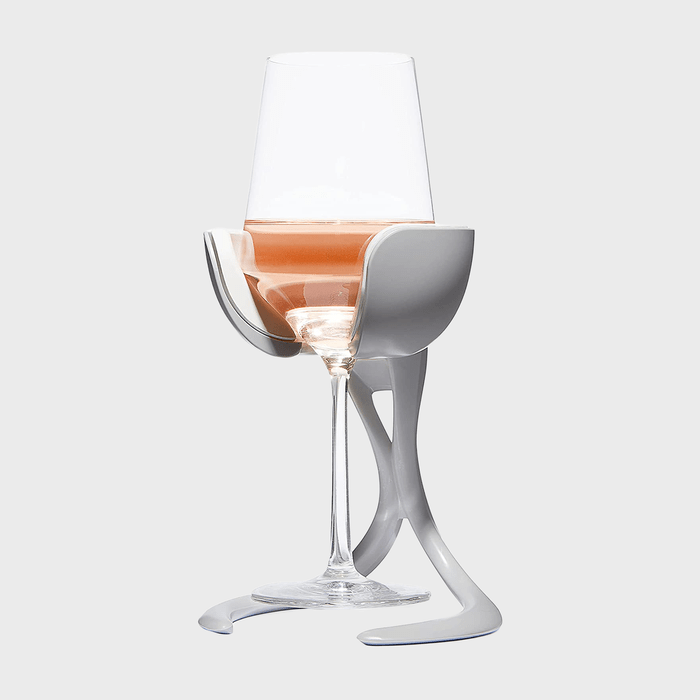 Glass sits in a modern, gray holder with legs, containing rosÃ© wine; isolated on a plain, light background.