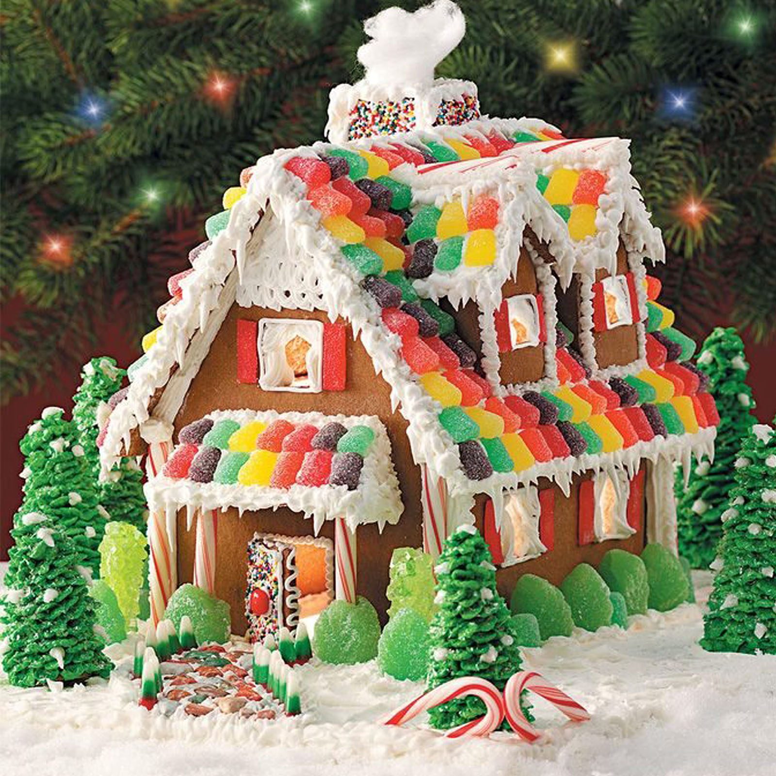 Gingerbread house stands decorated with colorful candies and frosting in a snowy setting with candy cane accents and green frosting trees.