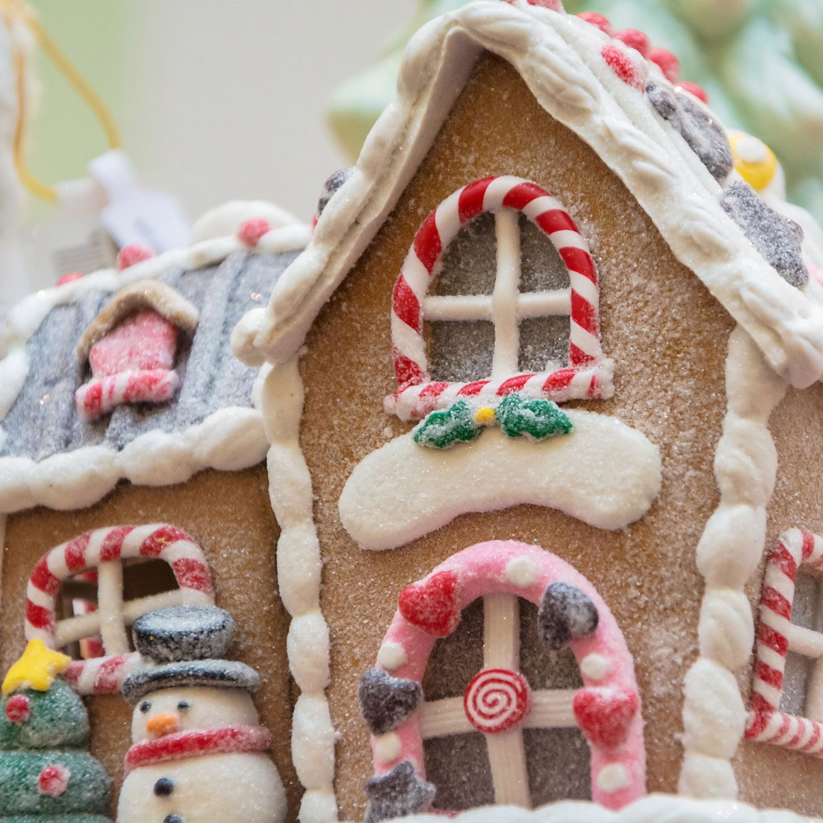 Gingerbread house adorned with icing, candy canes, and a snowman; festive decorations set within a holiday-themed environment.