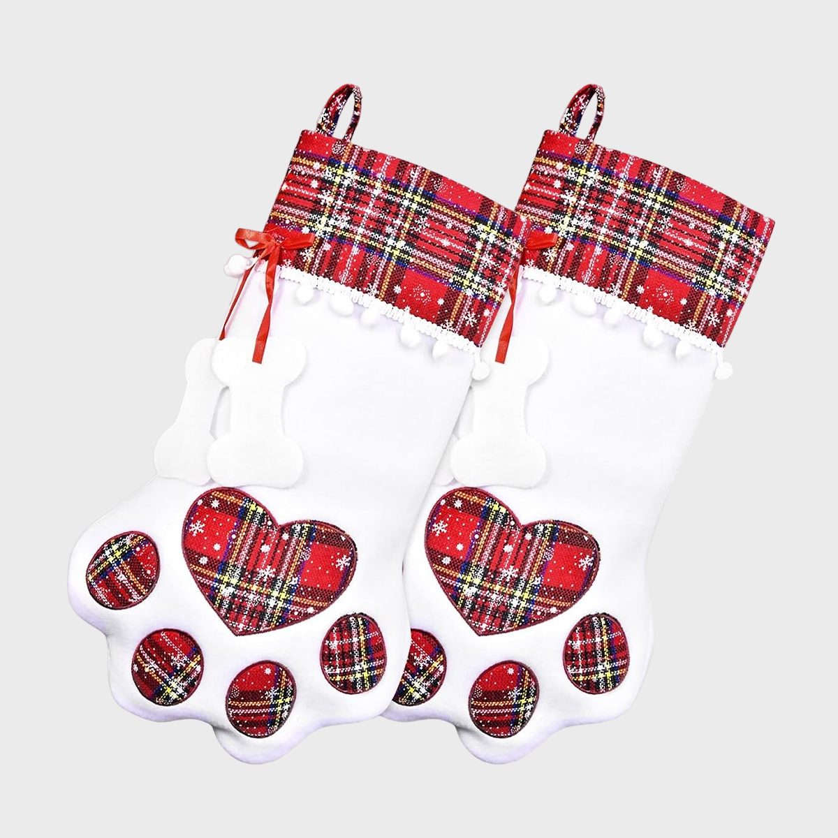 Two white stockings shaped like paw prints, feature red plaid patterns and bone details, hanging against a plain background.