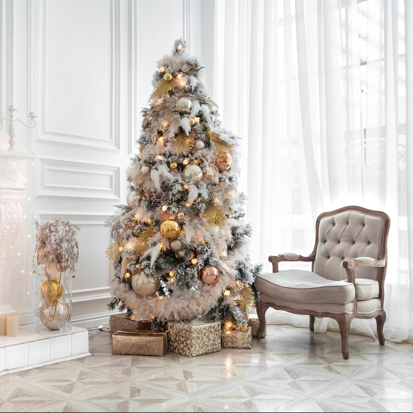 Classic white christmas interior with new year tree decorated. Fireplace with grey chair, clocks on the wall and presents under the tree