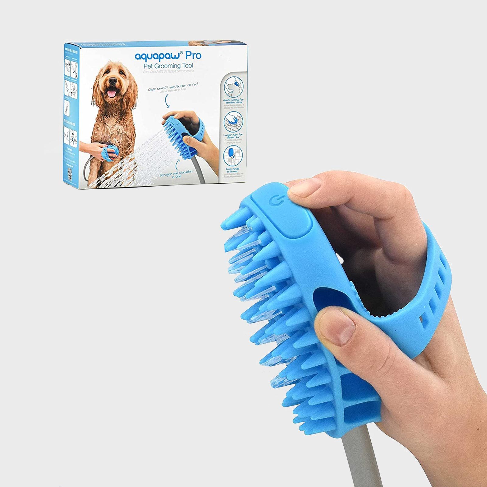 A blue pet grooming tool with protruding bristles is held in a hand. The packaging box shows a dog being groomed with the tool.