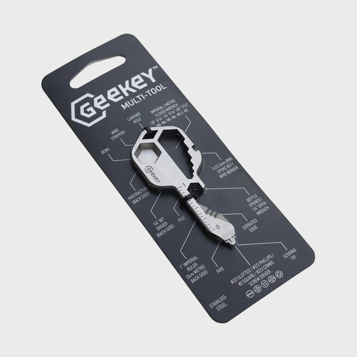 Key-shaped multi-tool lying on labeled black packaging, displaying various tool functions like wire stripper, file, and bottle opener in a minimalist design.