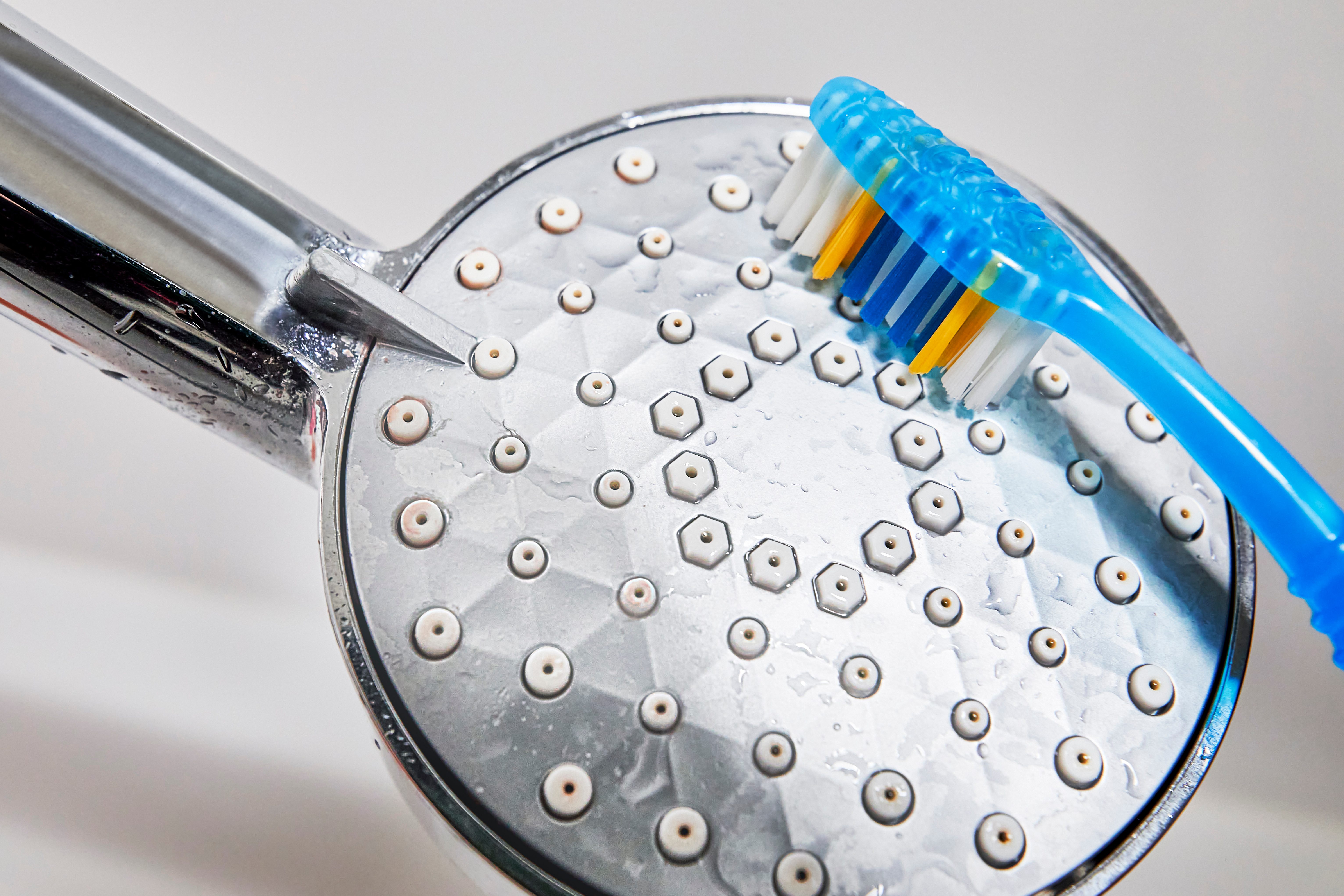 cleaning shower head with a toothbrush