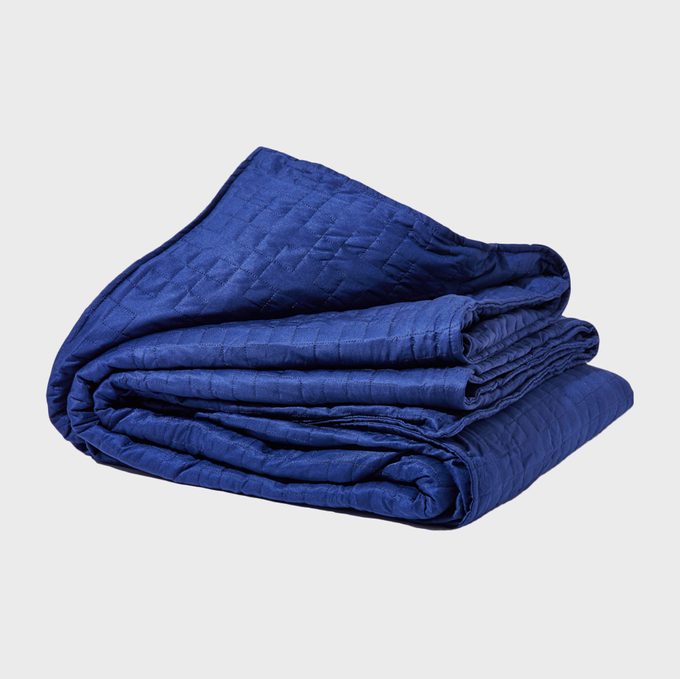 A folded blue quilt rests neatly on a flat, plain background.