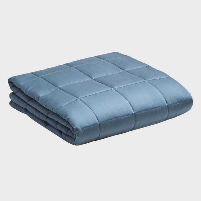 A folded, blue quilt sits on a plain, white background.