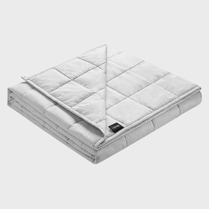 A folded, quilted gray blanket lies neatly on a flat white surface, showing a corner turned down, with a small black tag visible.