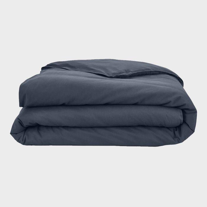 A folded, dark blue duvet sits neatly against a plain, light gray background.