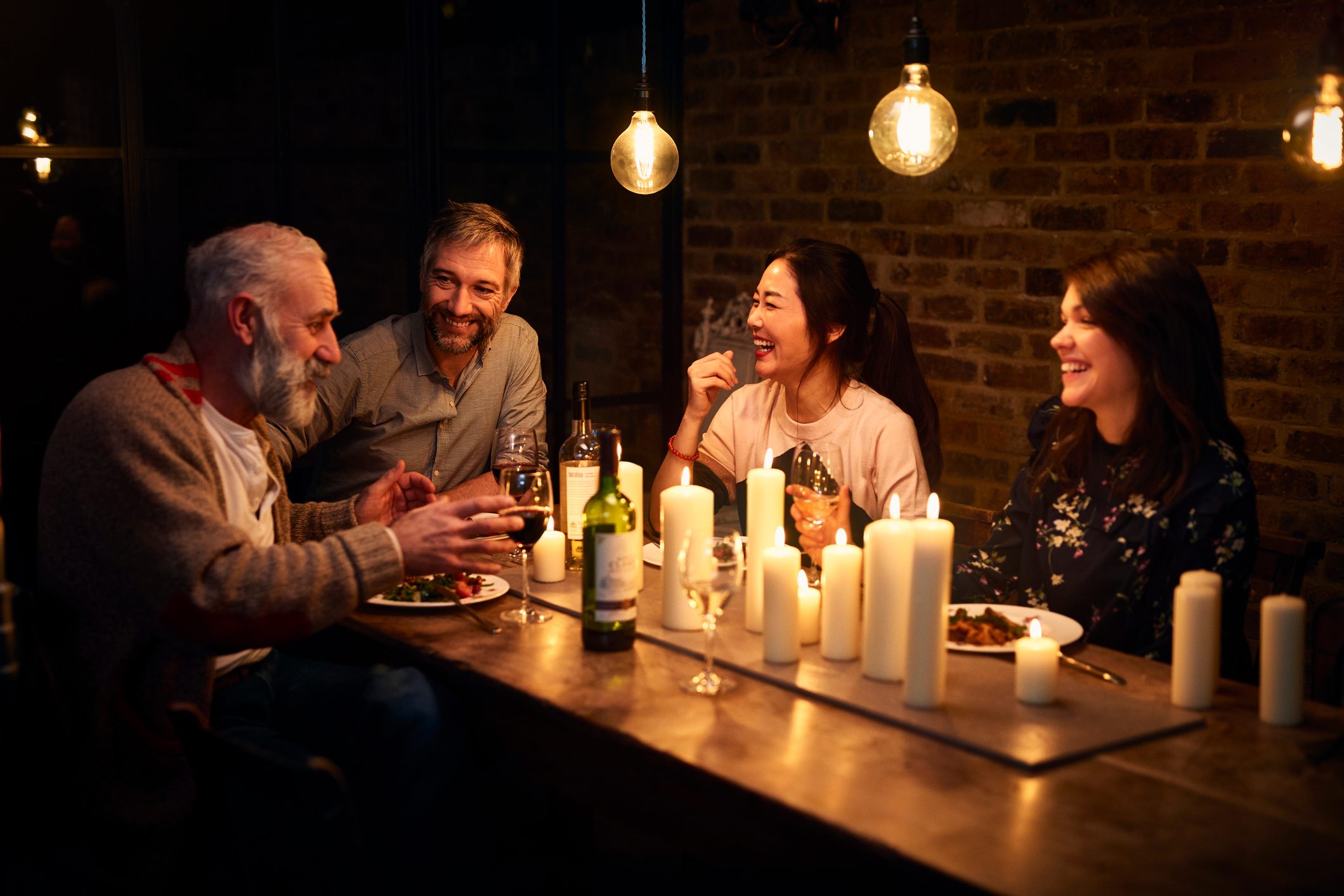 Four friends sitting at dinner and having conversation