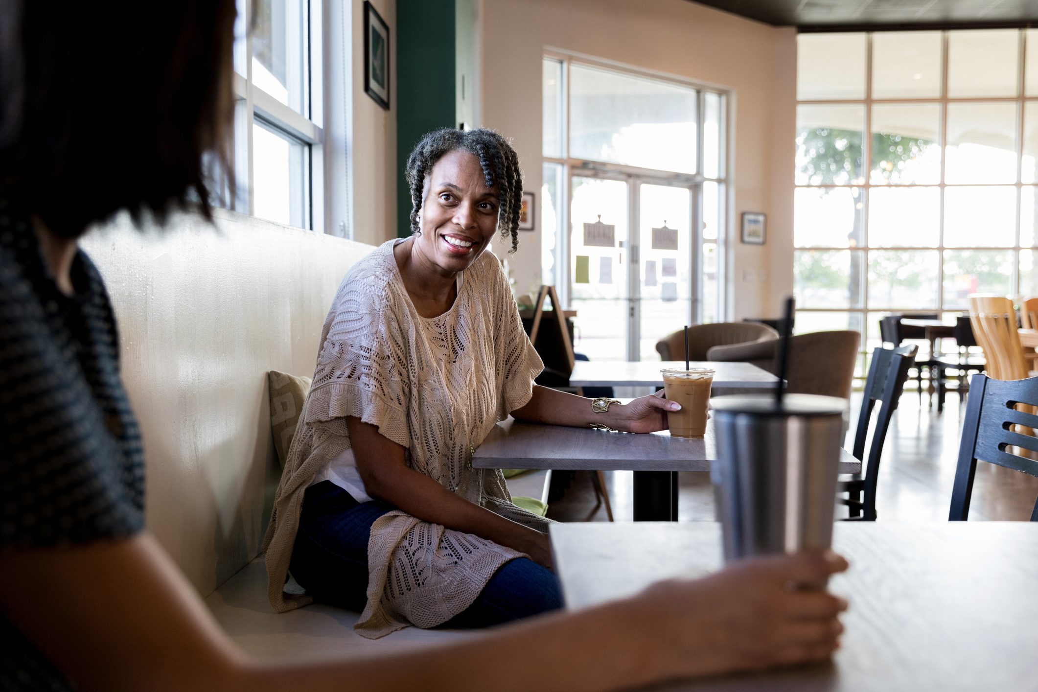 Women seated at separate tables speak with each other
