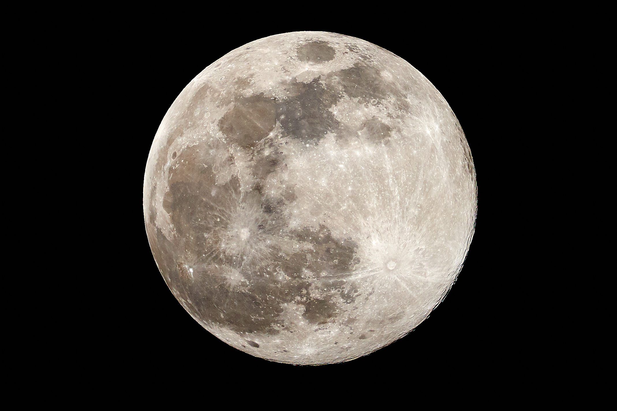 The moon appears full, showcasing detailed craters, set against a pitch-black sky.