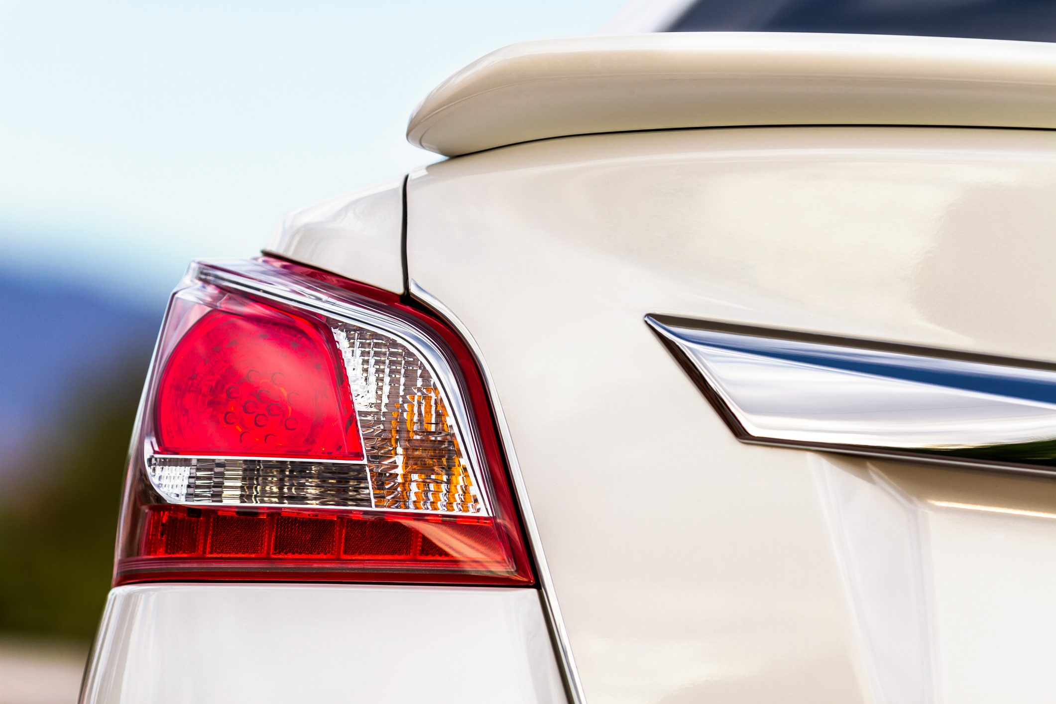 A car's rear light, showing red and amber sections, is illuminated against a blurred outdoor background.