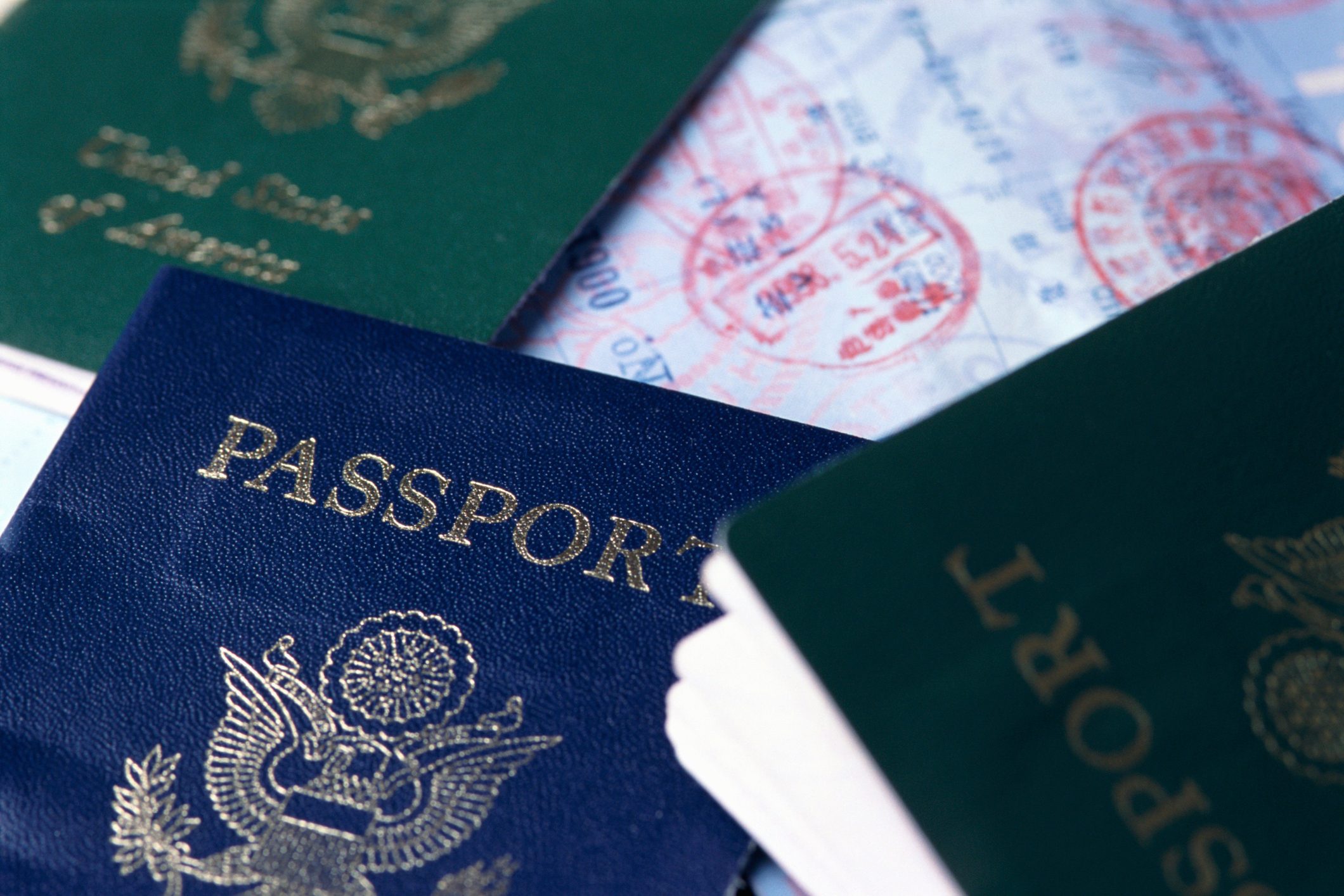 Passports overlap on a table with visible visa stamps, suggesting international travel.
