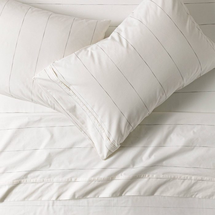 Two white pillows with thin black stripes lie on a matching striped bedsheet.