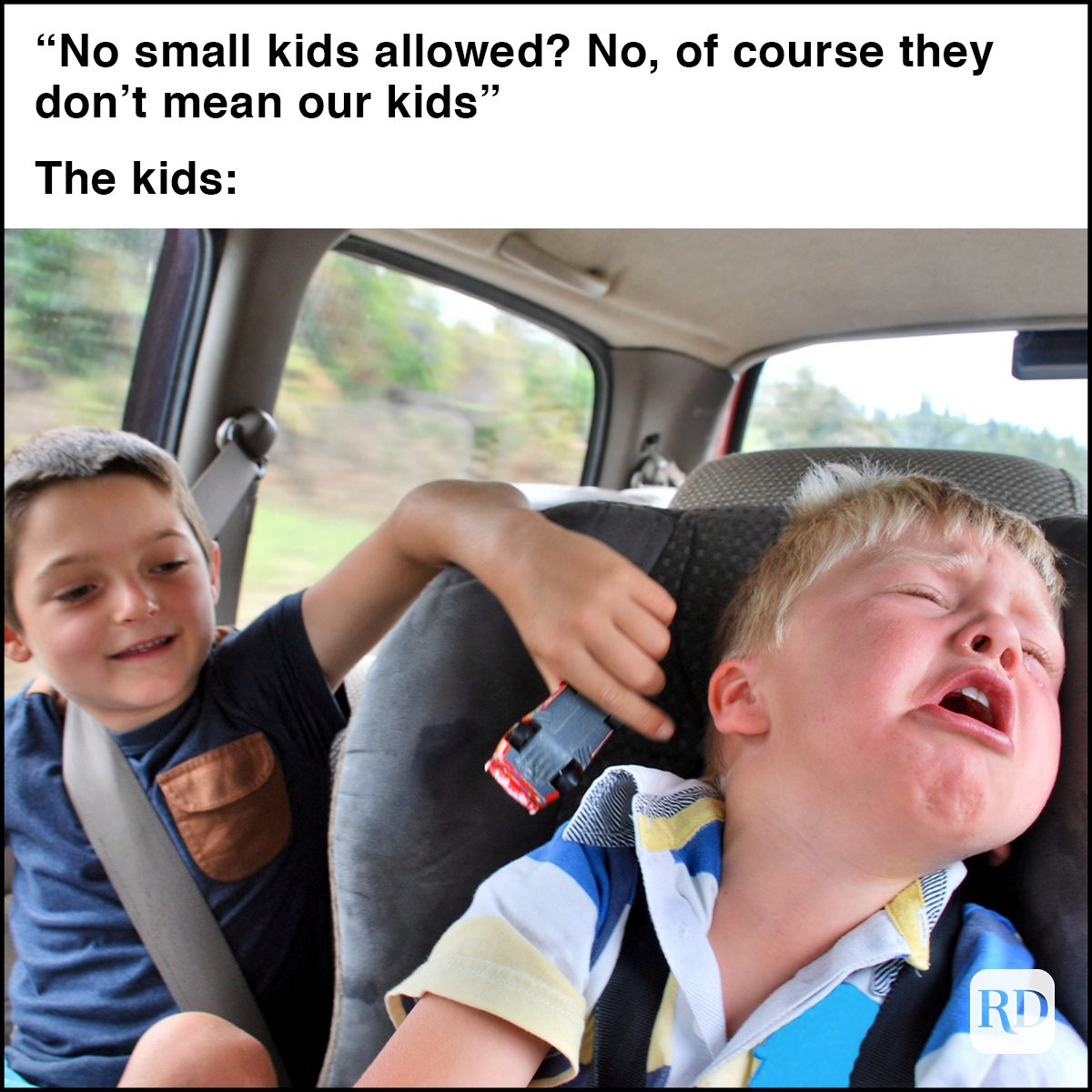 Looking into the back of the car at two children passengers passing the trip away teasing and crying.