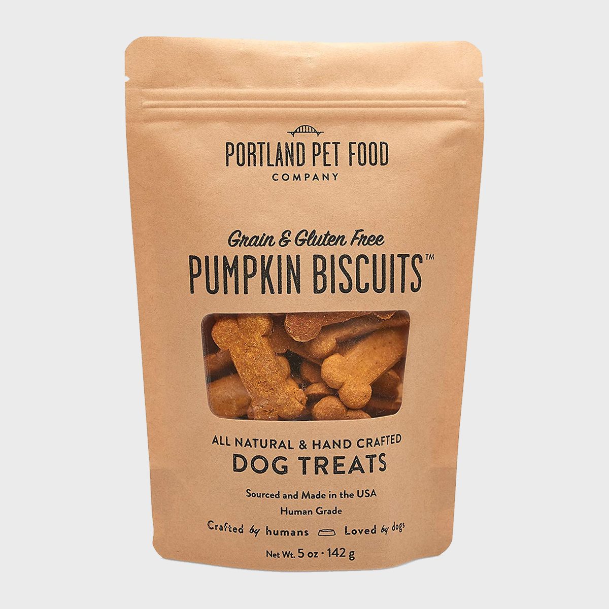 Bag contains grain and gluten-free pumpkin biscuits for dogs. Brown packaging displays text highlighting all-natural, handcrafted treats made in the USA.