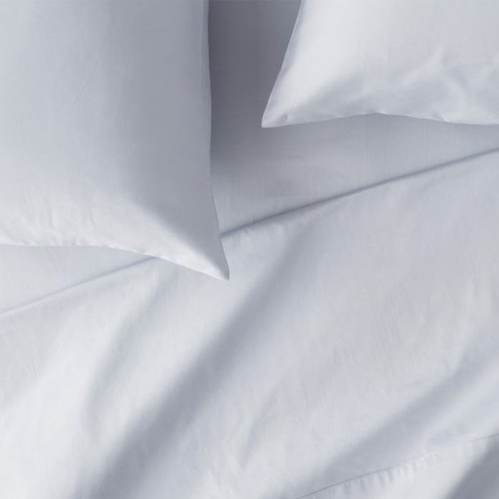Pillows lie on smooth, neatly arranged white bed sheets, creating a clean and restful bedroom atmosphere.