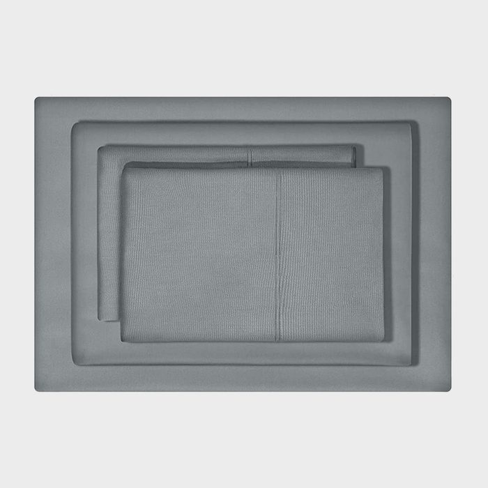 Folded gray bedsheets lie neatly layered against a plain background, showcasing their smooth texture and precise alignment.