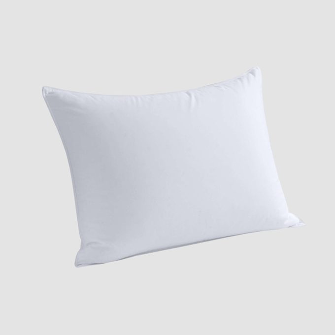 A white pillow rests at an angle against a plain, light gray background.