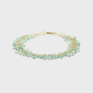 Bracelet displays light blue beads interwoven with golden chains, lying flat against a plain white background.