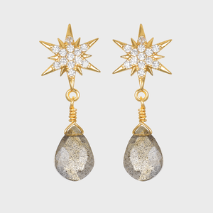 Gold earrings feature star-shaped tops and dangling teardrop-shaped stones, displayed against a plain background.