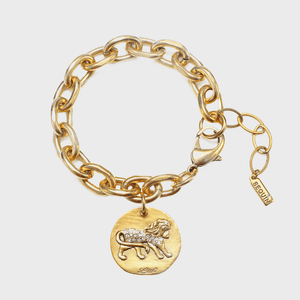 Gold bracelet features a lion-themed charm with crystal accents, linked by a chain; 