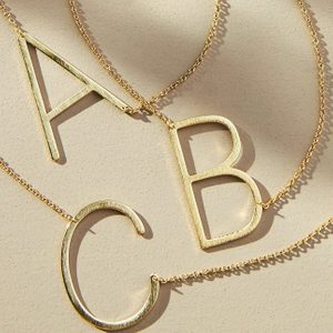 Gold necklaces display large letter pendants 