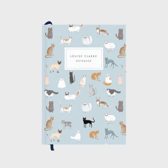 Notebook adorned with various illustrated cats on a light blue cover; features text reading 