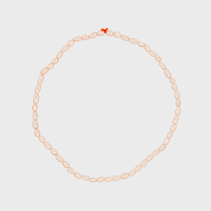 A pearl necklace forms a circle, secured with a small red clasp, on a plain white background.