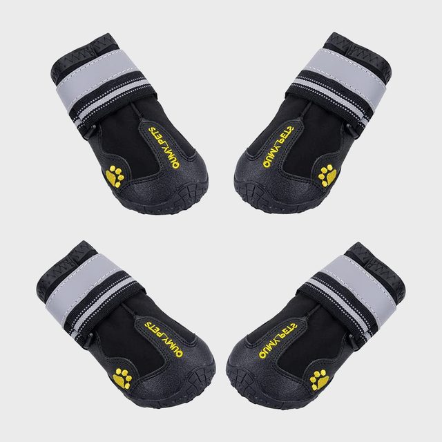 Four black dog boots lay against a plain background, featuring reflective straps and the 