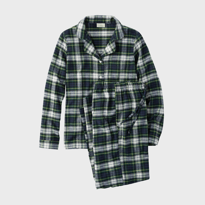 Plaid flannel pajamas lie folded on a light gray background, displaying a classic button-up shirt with matching pants.