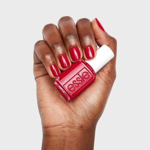 Hand holds a red nail polish bottle labeled 